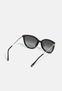 Black cat-eye sunglasses with gradient gray lenses. Features gold metal accents on the arms, plastic frame, and sleek design.