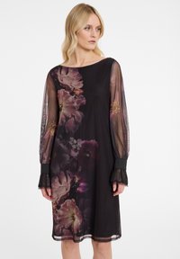 Schwarzes Blumenkleid mit durchsichtigen langen Ärmeln, das lila und pinke Blumenmuster sowie mit Spitze veredelte Bündchen aufweist. Einfaches, elegantes Design.