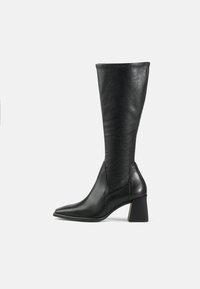 Botte noire en cuir montant jusqu'au genou avec un bout pointu et un talon carré. Texture lisse avec un design épuré et des détails de couture minimalistes.