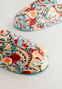 Bløde stofhjemmesko med farverigt abstrakt blomstermønster i rød, grønblå, orange og brun på en lys baggrund.