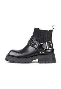 Botas de tobillo de cuero negro con una suela de goma gruesa, que cuentan con una correa de hebilla lateral, un panel elástico texturizado y una lengüeta.