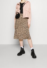 Jasnoróżowa krótka kurtka, czarna bluzka, midi spódnica w zwierzęcy wzór, masywne czarne botki, białe skarpetki i mała czarna torba na ramię.