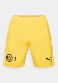 Gule atletikshorts lavet af glat stof. Har sorte logoer: et cirkul�ært mærke med "BVB 09" og tallet "1" til venstre, samt et Puma-logo til højre.