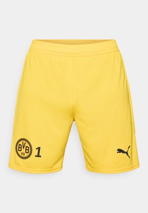 Gule atletikshorts lavet af glat stof. Har sorte logoer: et cirkulært mærke med "BVB 09" og tallet "1" til venstre, samt et Puma-logo til højre.