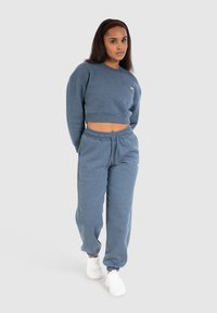 Sweatshirt cropped azzurro chiaro e pantaloni jogger abbinati in tessuto morbido, con un taglio rilassato e polsini elasticizzati, abbinati a sneakers bianche.