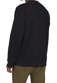 Svart sweatshirts med rund hals, långa ärmar och ribbade muddar. Tillverkad av ett mjukt, texturerat tyg. Enkel design utan dekorationer.