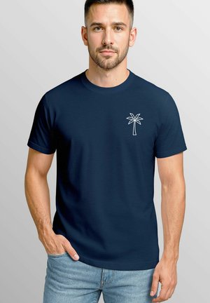 Navy blue t-shirt in cotton blend, featuring a small white palm tree graphic on the left chest. Crew neck and short sleeves.