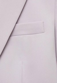 Helllila Stoff eines Anzugsjackets mit einer Brusttasche und sauberem Finish. Die Textur ist glatt und strukturiert und zeigt subtile Webmuster.
