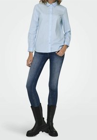 Light blue striped button-up shirt with long sleeves, paired with dark blue skinny jeans and black knee-high boots. Smooth fabric, casual style.