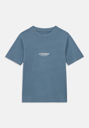 Zils īsroku kokvilnas T-krekls ar apaļu kakla izgriezumu un baltu "JJ Studios" logotipu, kas izvietots centrā uz krūtīm.