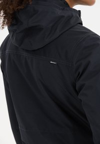 Giacca impermeabile nera con cappuccio, caratterizzata da una texture liscia, un sottile dettaglio del marchio e cuciture a contrasto lungo le cuciture.