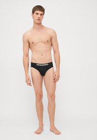 Schwarze Slips mit strukturiertem Bund, der den Markennamen "DSQUARED2" in weißer Schrift zeigt.
