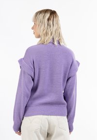 Pulover tricotat lavandă cu o croială lejeră, manșete cu nervuri și design cu umeri despărțiți. Țesătură texturată cu un finisaj moale.