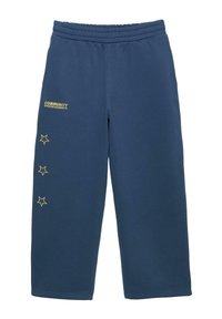 Marineblauwe sweatpants met elastische tailleband, drie gele stercontouren verticaal op het linkerbeen en de tekst "COMMUNITY UPDATED GARMENTS" nabij de linkerzak.