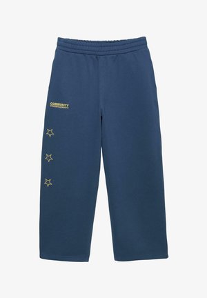 Granatowe spodnie dresowe z elastycznym pasem, trzema żółtymi konturami gwiazd ułożonymi pionowo na lewej nogawce oraz napisem „COMMUNITY UPDATED GARMENTS” w pobliżu lewego kieszenia.