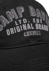Schwarze Baseballmütze mit gesticktem Text "CAMP DAVID" und "ORIGINAL BRAND" in Grau. Sie hat sichtbare Nähte und einen gebogenen Schirm.
