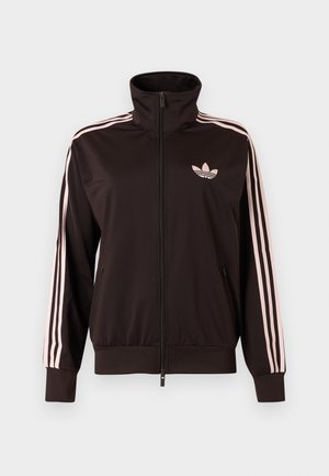 Veste de survêtement zippée noire avec trois bandes roses sur les manches et logo trèfle Adidas rose sur la poitrine gauche, col montant, poches avant.