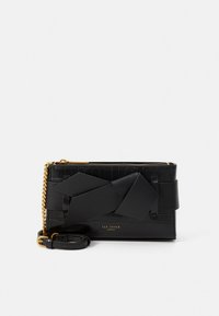 Mala tipo carteira preta de pele vegan com textura de crocodilo, detalhe de laço grande, alça de corrente dourada e logótipo em letras douradas.