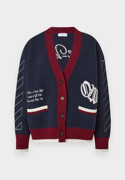 Granatowy sweter z dzianiny z bordowym, prążkowanym kołnierzem i mankietami, z białą haftowaną aplikacją, dwiema przednimi kieszeniami i dekoracyjnymi ukośnymi paskami.