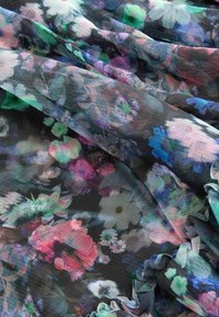 Tissu noir transparent avec un motif floral multicolore en nuances de rose, bleu, vert et blanc, drapé et rassemblé doucement.