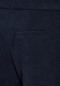 Navy blauwe joggers gemaakt van zacht ribbelstof met een discrete achterzak, die een strakke en gestroomlijnde uitstraling hebben.