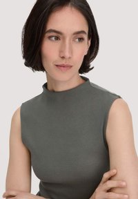 Ärmelloses Top mit hochgeschlossenem Kragen aus olivgrünem Rippstoff. Glatte Textur mit subtiler Dehnbarkeit, entworfen für eine figurschmeichelnde Silhouette.