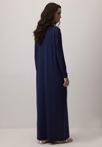 Garais piedurkņu, grīdas garuma kleita no vienkrāsaina tumši zila auduma ar brīvu piegriezumu un mīkstu tekstūru, ar pieguļošām piedurknēm un vienkāršu dizainu.