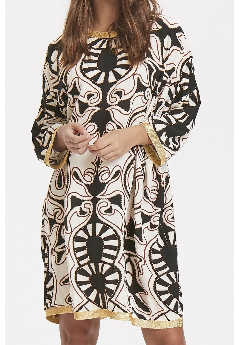 Robe à motifs avec un design noir et blanc orné de détails dorés. Manches longues et coupe ample avec un col rond.