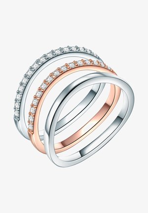 Tričko prepletené prstene: jeden strieborný s priehľadnými kryštálmi, jeden ružovo-zlatý s menšími priehľadnými kryštálmi a ďalší hladký strieborný prsteň.