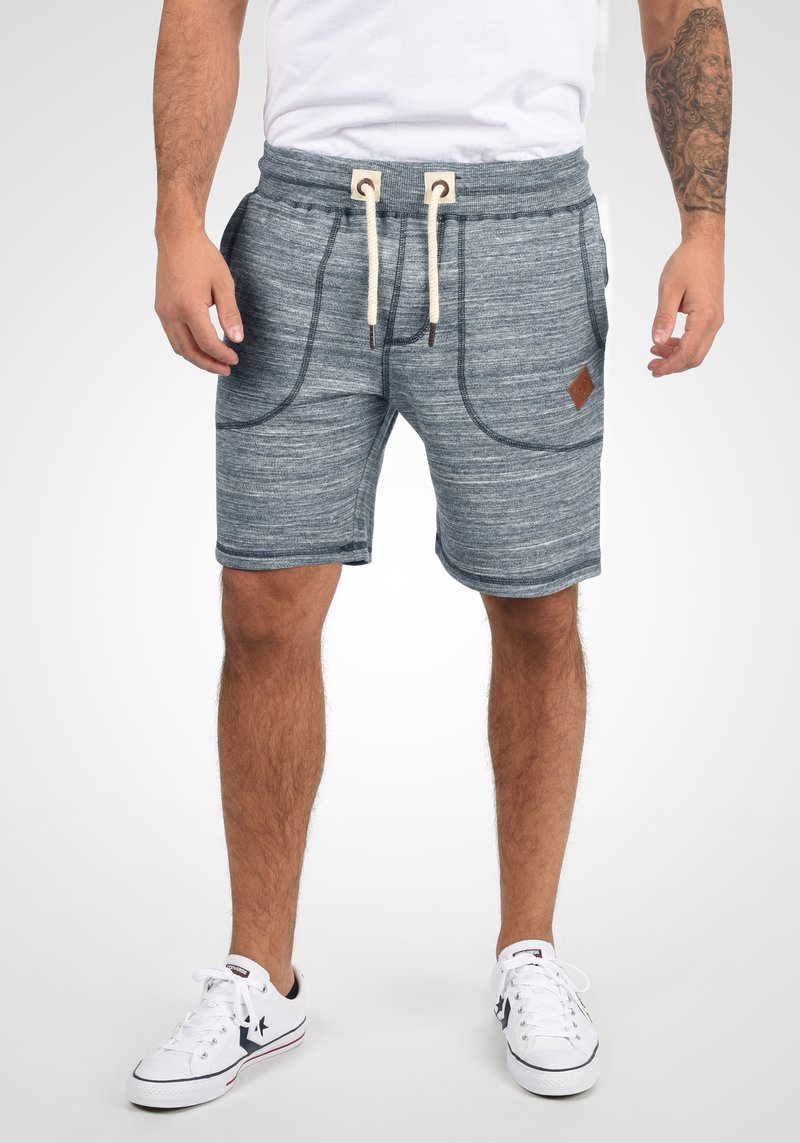 Pantalones cortos de mezcla gris con una cinturilla elástica, cordón y dos bolsillos laterales. Presentan una tela texturizada y un acento de logo de cuero marrón.
