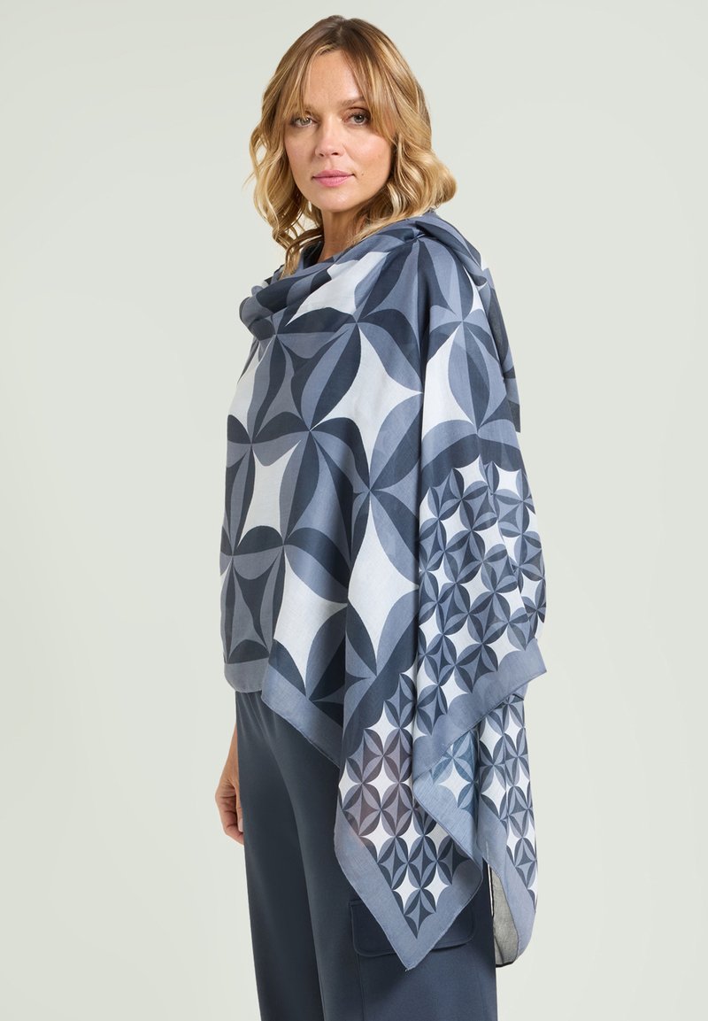 Pañuelo cuadrado en tonos azules con patrones geométricos. Fabricado con tela ligera de textura suave y bordes enrollados.