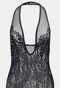 Svart nätbodysuit med djup V-ringning, som har ett texturerat tyg och ett djärvt öppet vävmönster genom hela plagget, med minimalistiska axelband.