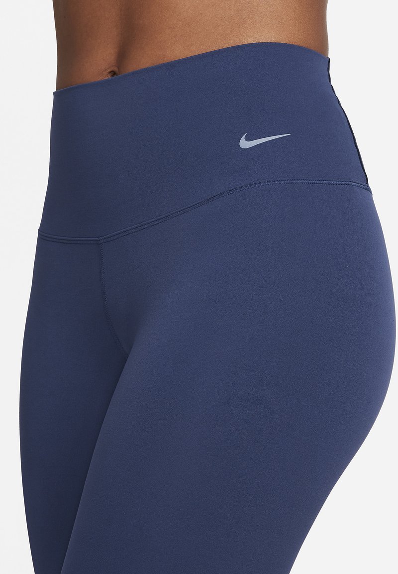 Navy-farbene High-Waist-Leggings aus dehnbarem Stoff. Sie haben eine glatte Oberfläche und ein kleines silbernes Logo am Bund.