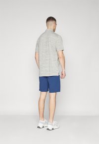 Gray, short-sleeve polo shirt and blue shorts. The polo has a textured pattern; shoes are white with gray accents.