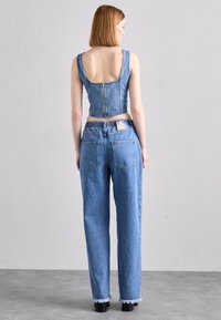 Denim cropped top s širokim naramenicama i zatvaračem na leđima, uparen s trapericama visokog struka s isfrabanim rubom i elastičnom gumicom.