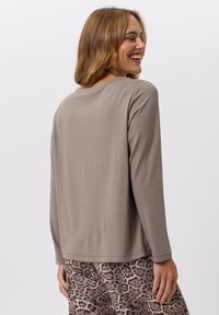 Haut taupe à manches longues avec un col rond, texture lisse et coupe décontractée, associé à un bas à imprimé léopard.