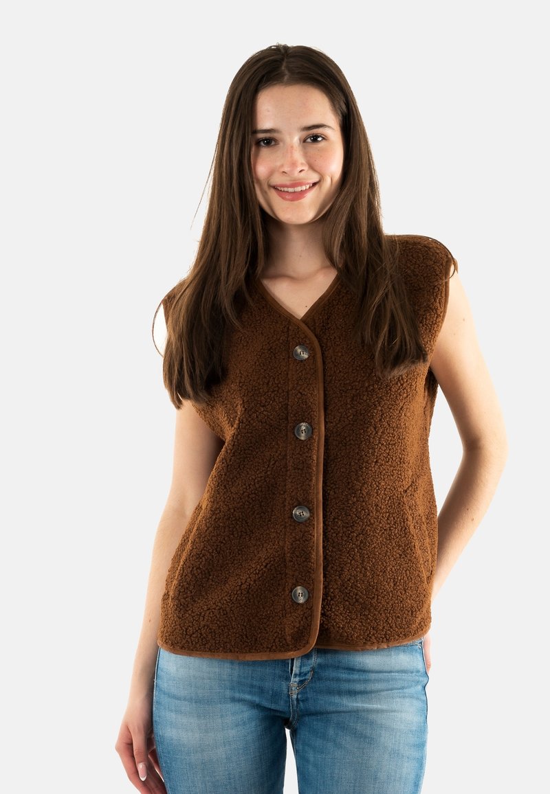 Gilet in pile marrone con scollo a V, maniche corte e cinque bottoni argento. Presenta una superficie testurizzata e un bordo a contrasto. Indossato sopra un paio di jeans.