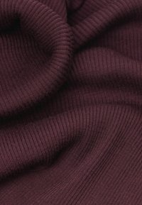 Burgunderfarbenes geripptes Strickgewebe mit einer weichen Textur und welligen Falten, die feine Linien und einen leichten Glanz aufweisen.