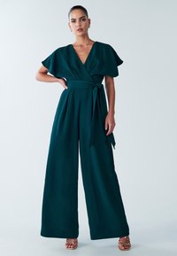 Teal jumpsuit with a deep V-neck, flutter sleeves, and a tied waist, featuring wide legs and a smooth, textured fabric.
