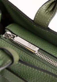 Sac à main en cuir vert avec une fermeture éclair argentée, une surface texturée, et une étiquette avec "PICARD depuis 1920" embossée sur la tirette de la fermeture éclair.