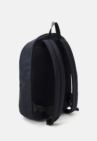 Sac à dos noir avec des bretelles rembourrées et doublées en mesh, et un extérieur lisse et durable. Le design est simple, avec une poignée de transport supérieure.