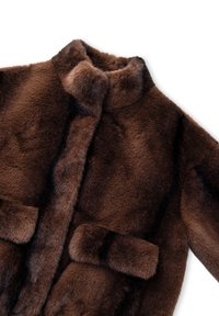 Brauner Kunstfellmantel mit hohem Kragen, weicher Textur, zwei vorderen Taschen und einem leicht übergroßen Design. Keine sichtbaren Verschlüsse.