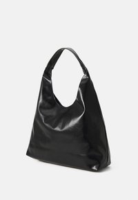 Černá kožená hobo taška s zakřiveným držadlem, měkkou strukturou a volným tvarem. Má bezešvou konstrukci a minimální ozdoby.