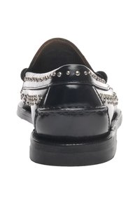 Mocassins en cuir noir avec accents cloutés, texture lisse, bout rond et petit talon. La vue arrière met en évidence les coutures et le matériel décoratif.