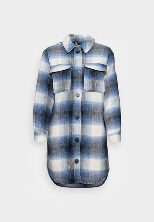 Veste à carreaux bleus et blancs, avec un devant à boutons, deux poches poitrine, un col et un ourlet arrondi.