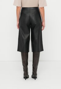 Μαύρα δερμάτινα κουλότ με ψηλή μέση και δύο πίσω τσέπες, με απαλή υφή και σχεδιασμό με φαρδύ πόδι.