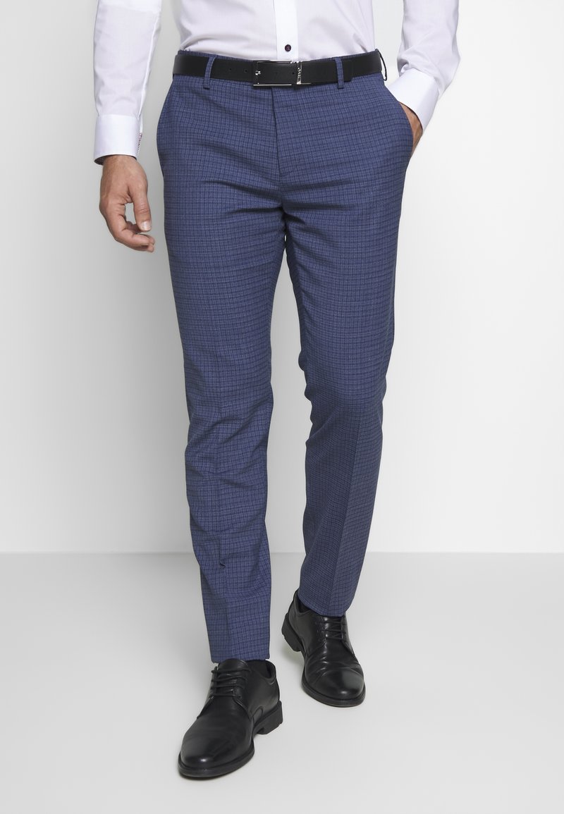Tailored dress pants in blue with a subtle check pattern, featuring a flat front, side pockets, and a black belt, paired with black shoes.