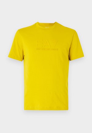T-shirt in cotone giallo con scollo a girocollo, caratterizzata da un logo EA7 in rilievo sul davanti. Maniche corte e texture liscia.