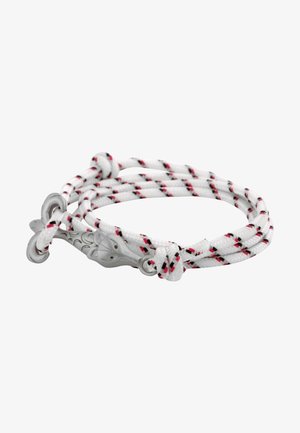 Corde blanche enroulée avec des rayures rouges et noires et une boucle métallique argentée en forme de tête d’animal sur fond blanc.