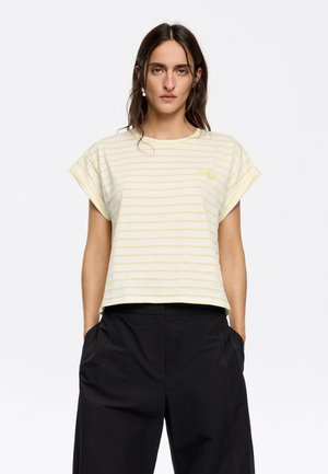 T-shirt a maniche corte di colore giallo chiaro a righe, con vestibilità comoda e scollatura rotonda. Presenta testo ricamato nella zona sinistra del petto.